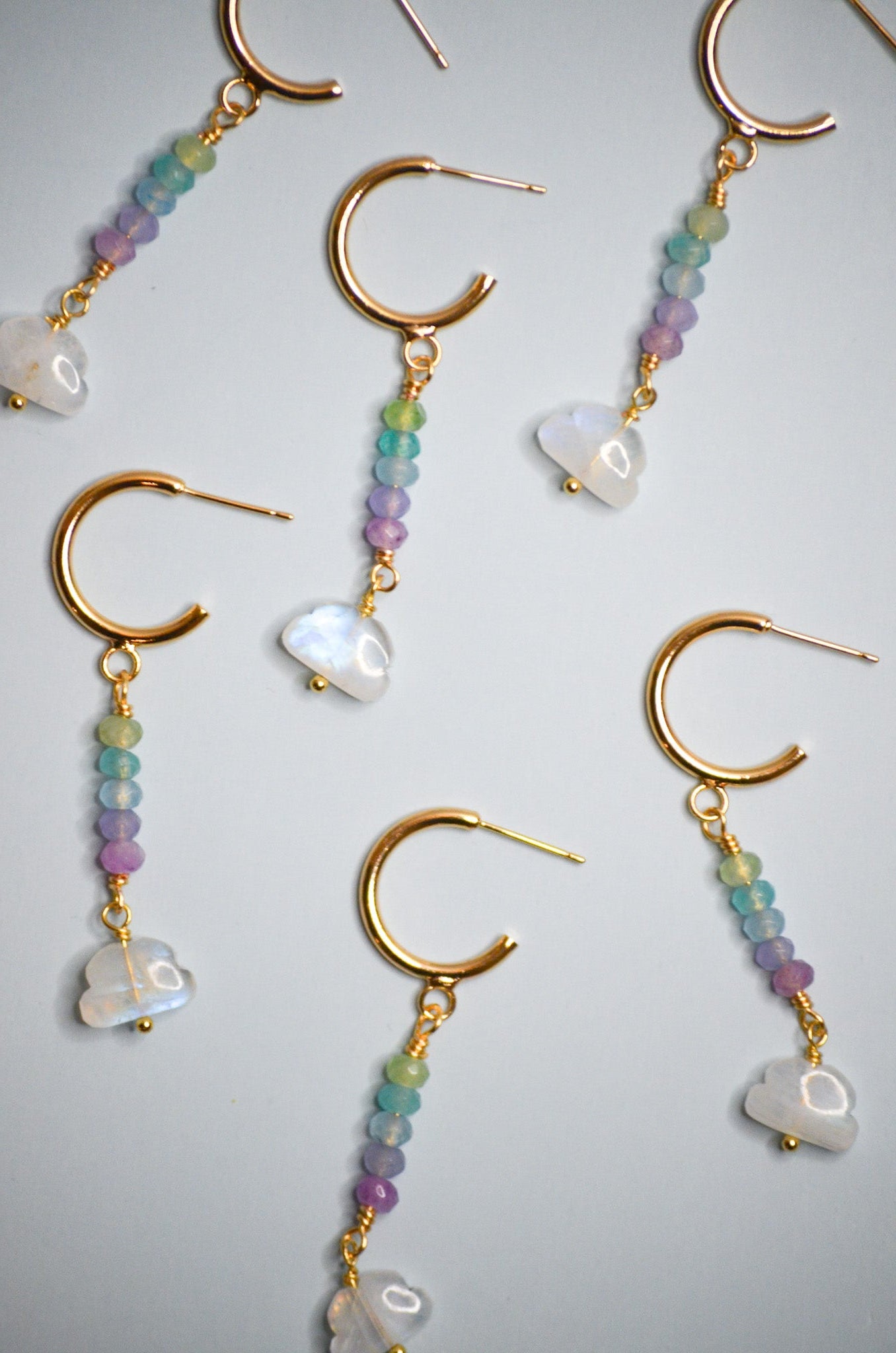 Gold beaded cloud dangle earrings with colorful beads on a light blue background