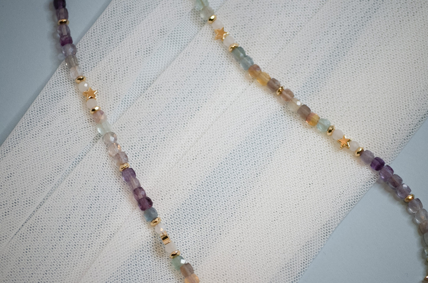 Necklace with multicolored and gold star beads on a textured fabric background