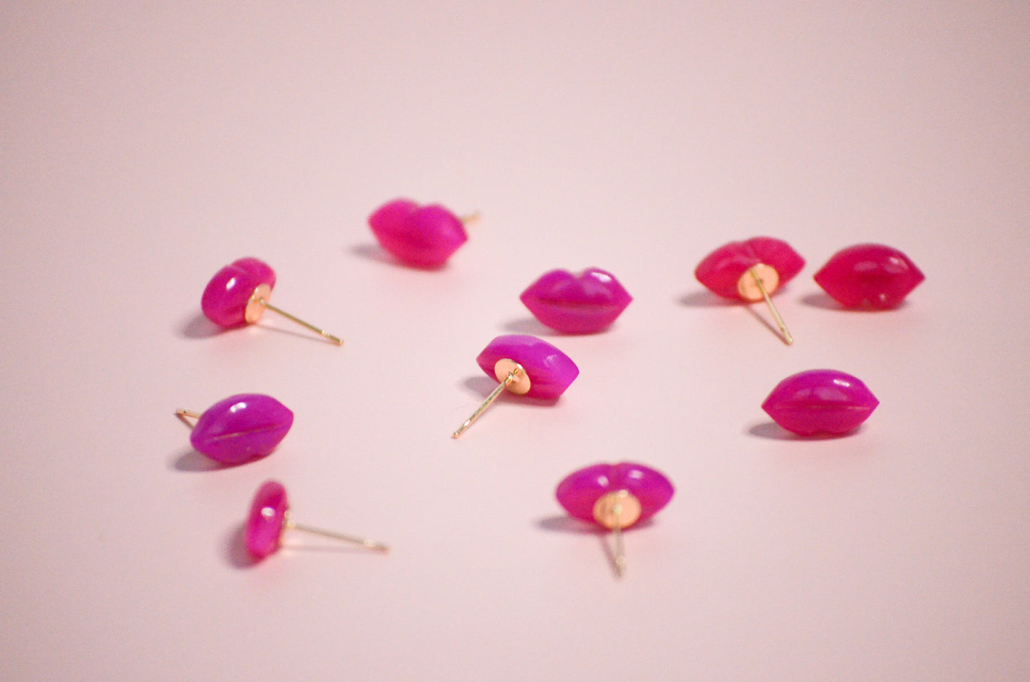 Pink lip-shaped with gold post earrings on a pink background