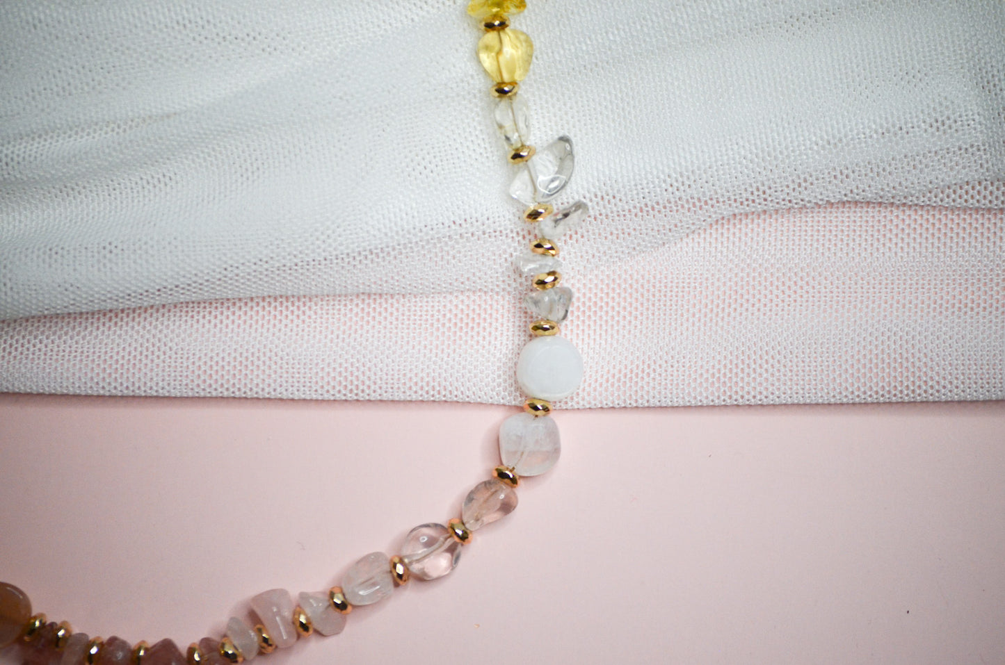 Necklace with warm toned and gold beads on a light fabric background