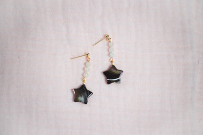 Star-shaped earrings on a light pink fabric background