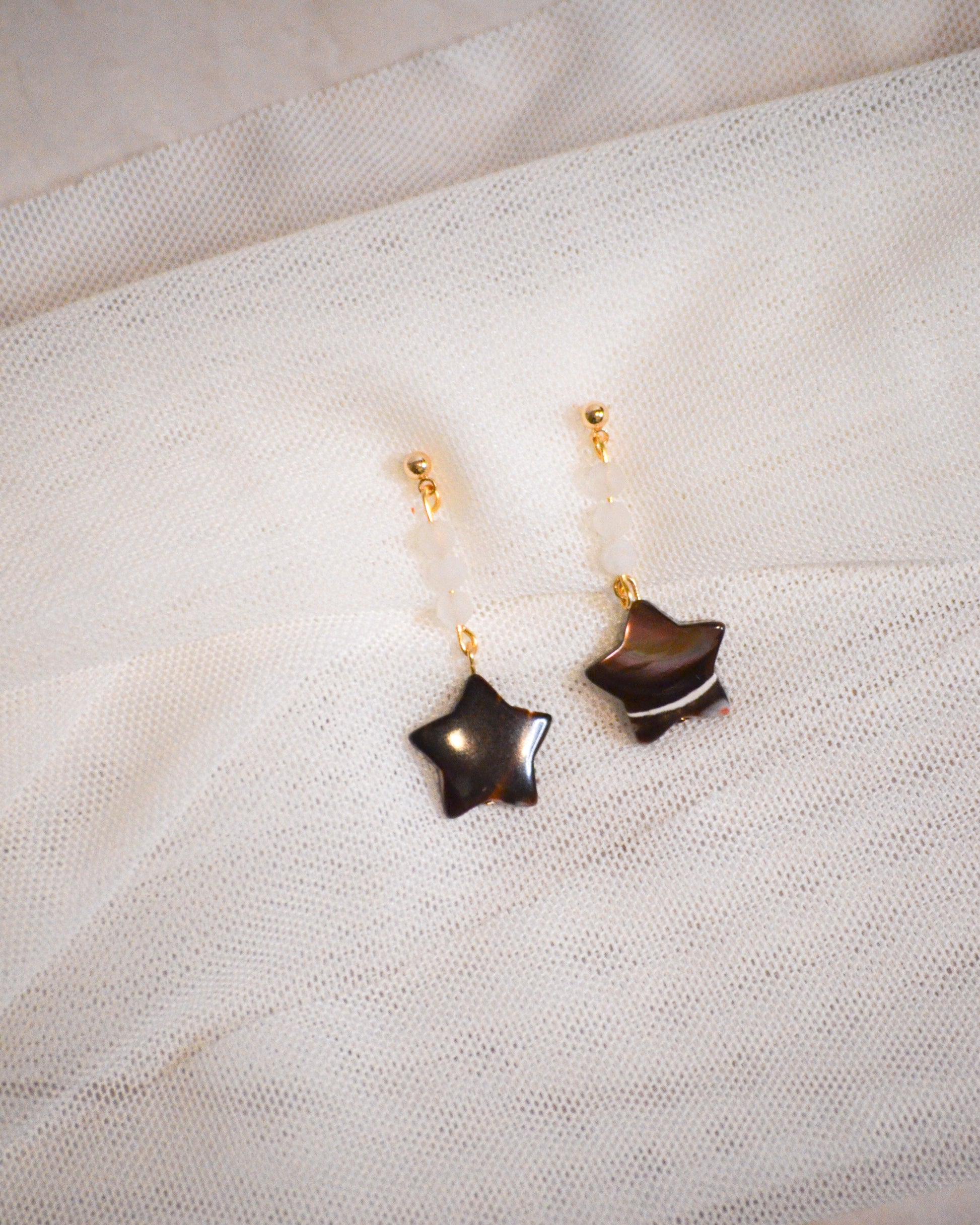 Star-shaped earrings on a textured white fabric background