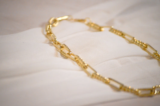 Gold chain necklace on a white fabric background