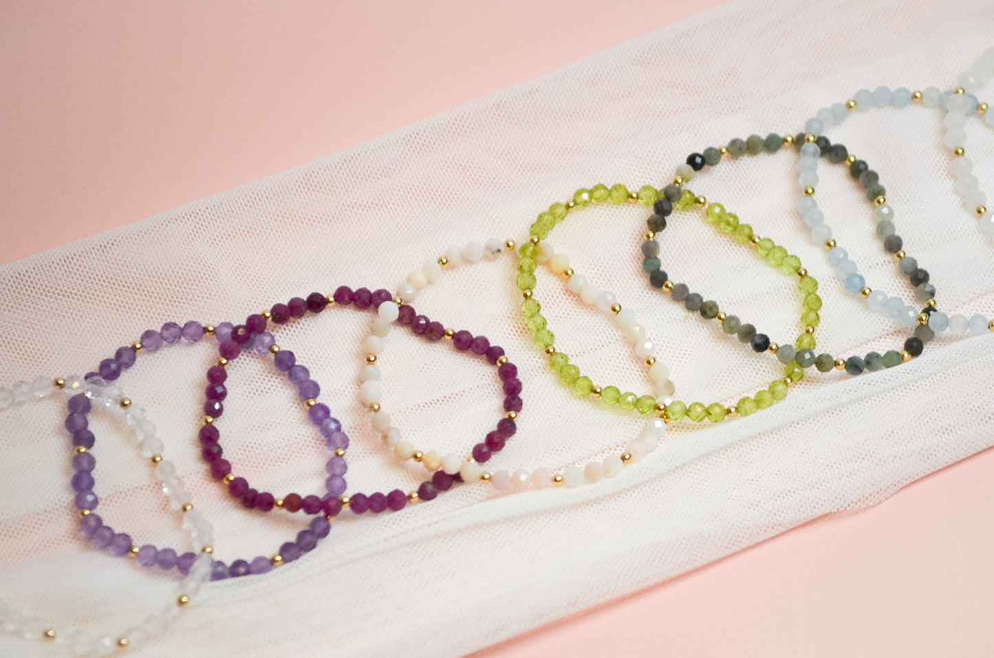 Set of beaded bracelets on a white fabric with a pink background
