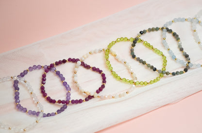 Set of beaded bracelets on a white fabric with a pink background