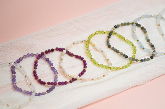 Set of beaded bracelets on a white fabric with a pink background
