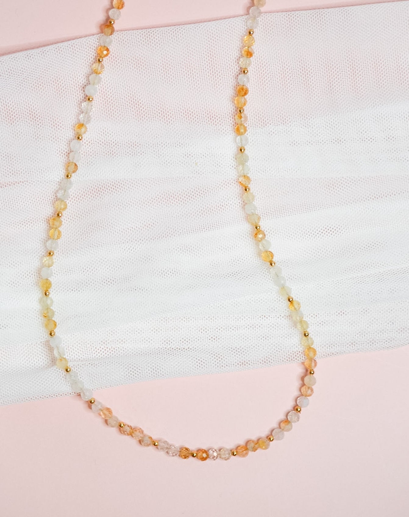 Citrine beaded necklace on a textured fabric background