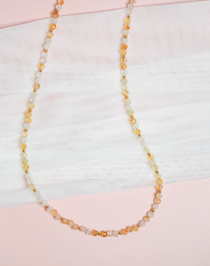 Citrine beaded necklace on a textured fabric background