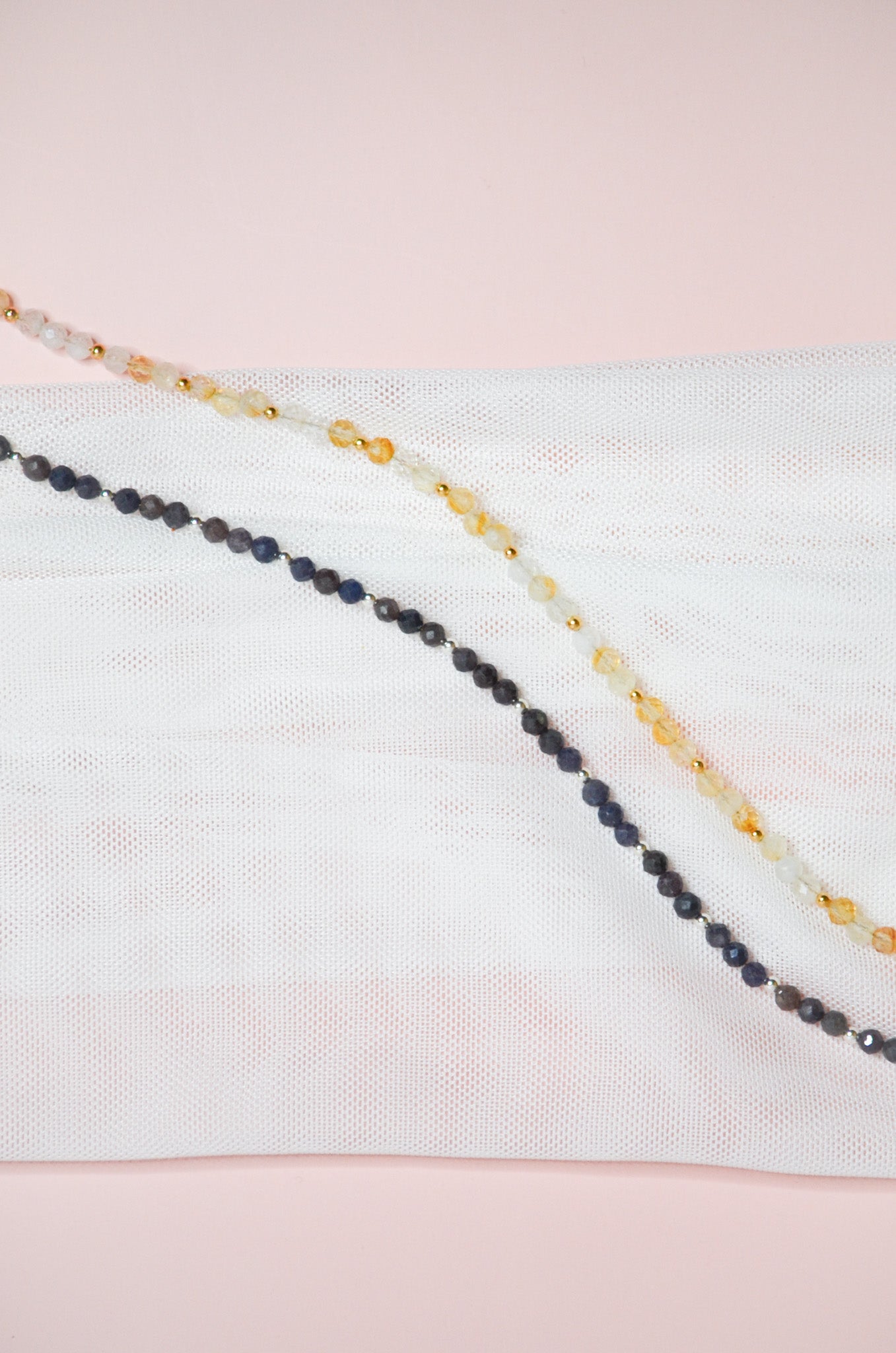 Two beaded necklaces on a light pink and white background