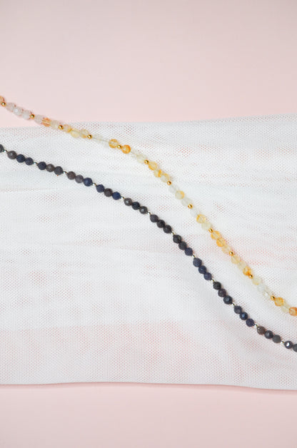 Two beaded necklaces on a light pink and white background