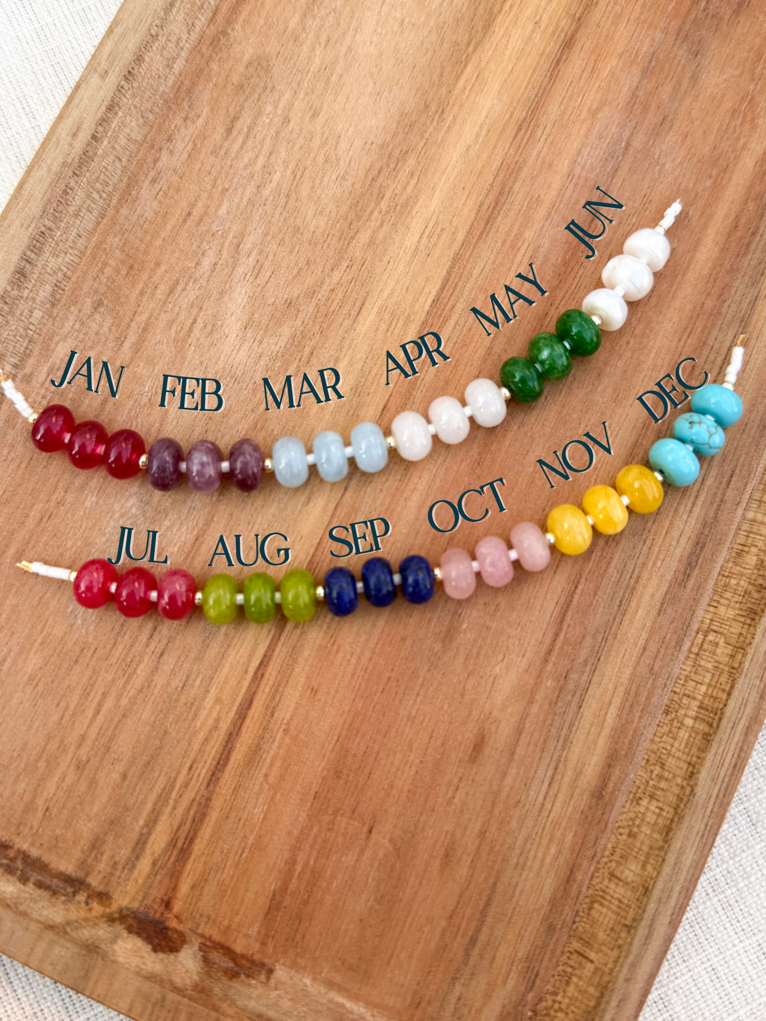 Colorful beaded sticks with months labeled on a wooden surface