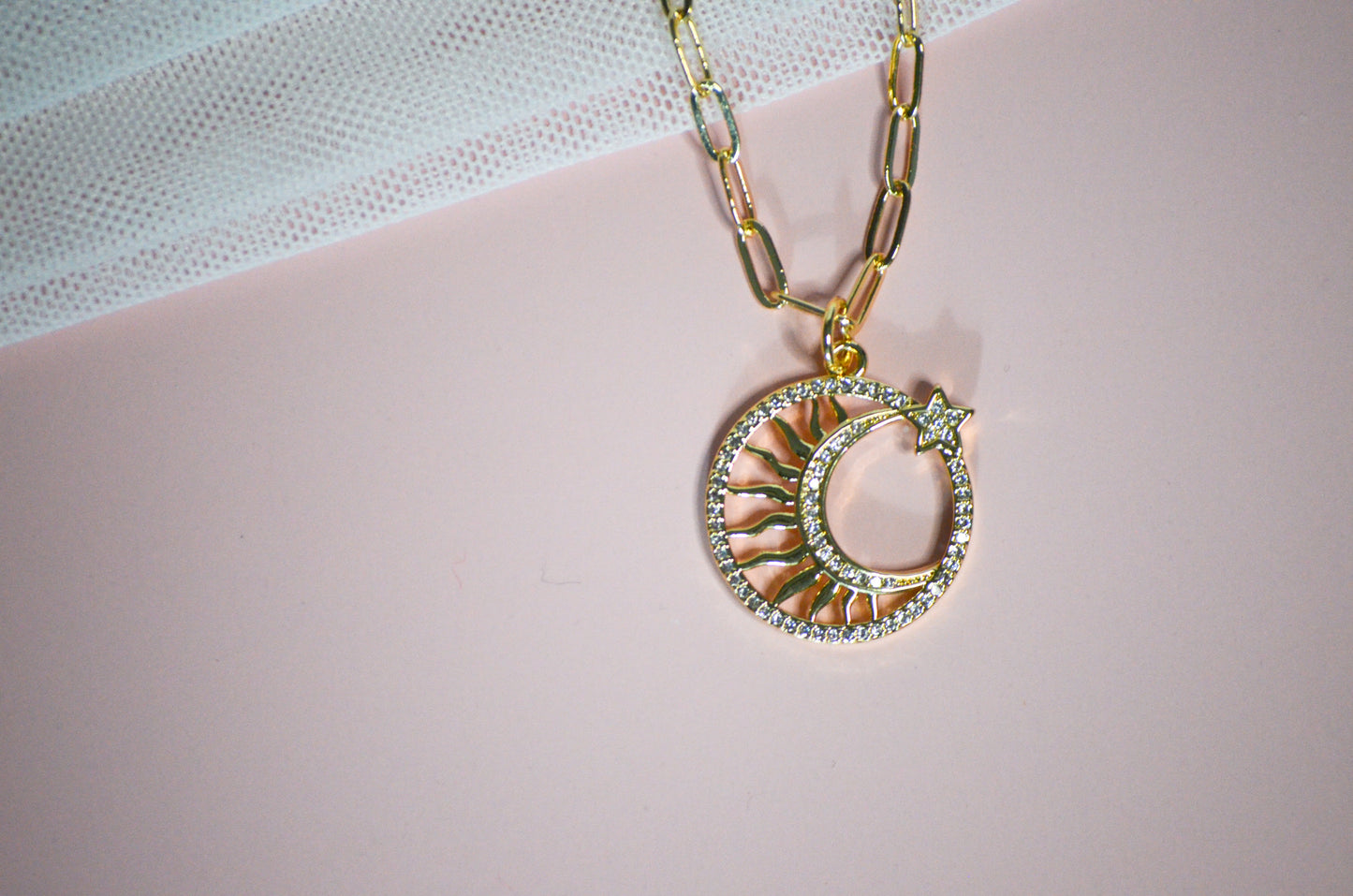 Necklace with a crescent moon and star pendant on a pink surface