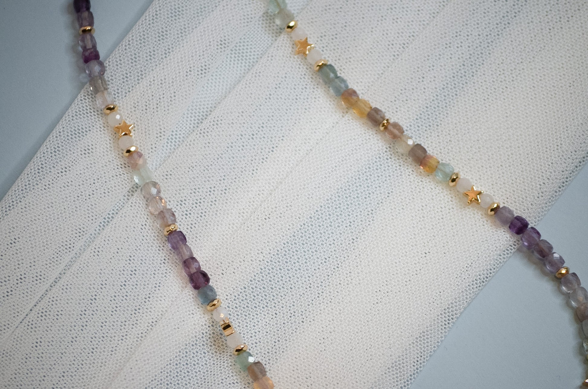 Necklace with multicolored and gold star beads on a textured fabric background