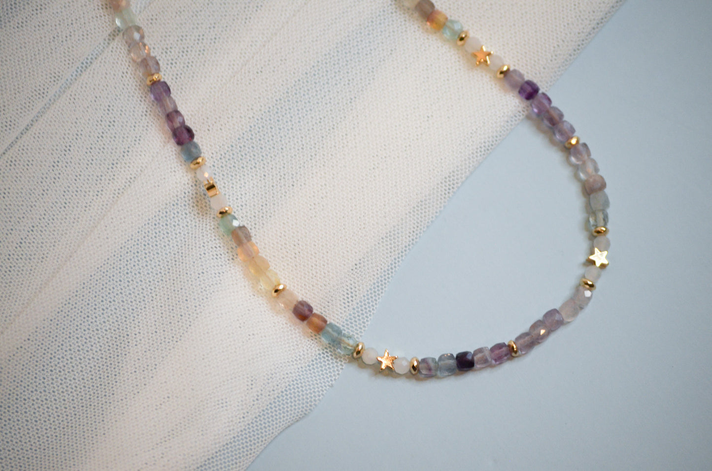 Multicolored and gold stat beaded necklace on a textured fabric background