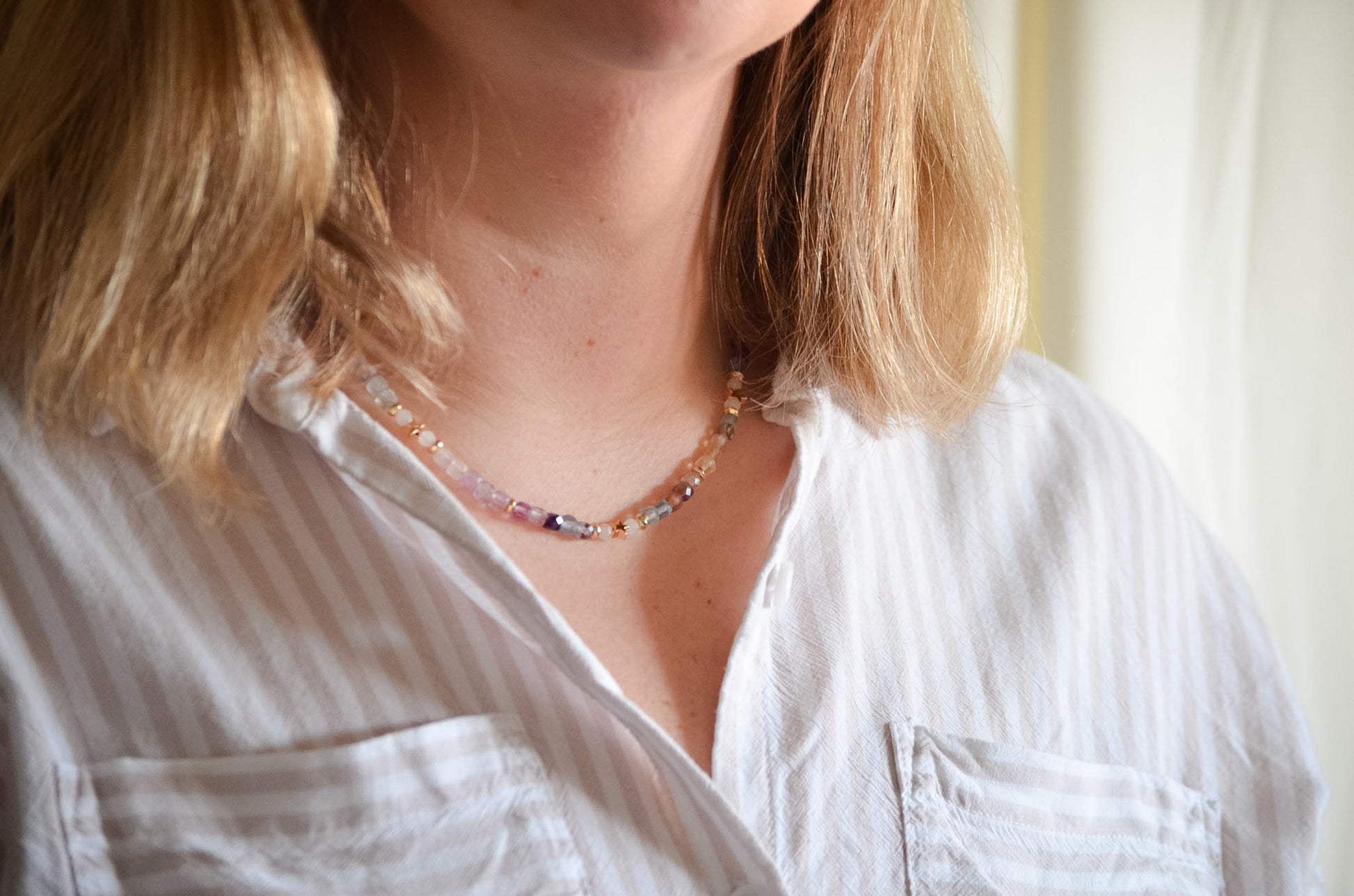 Close-up of a person wearing a white shirt and a colorful necklace.