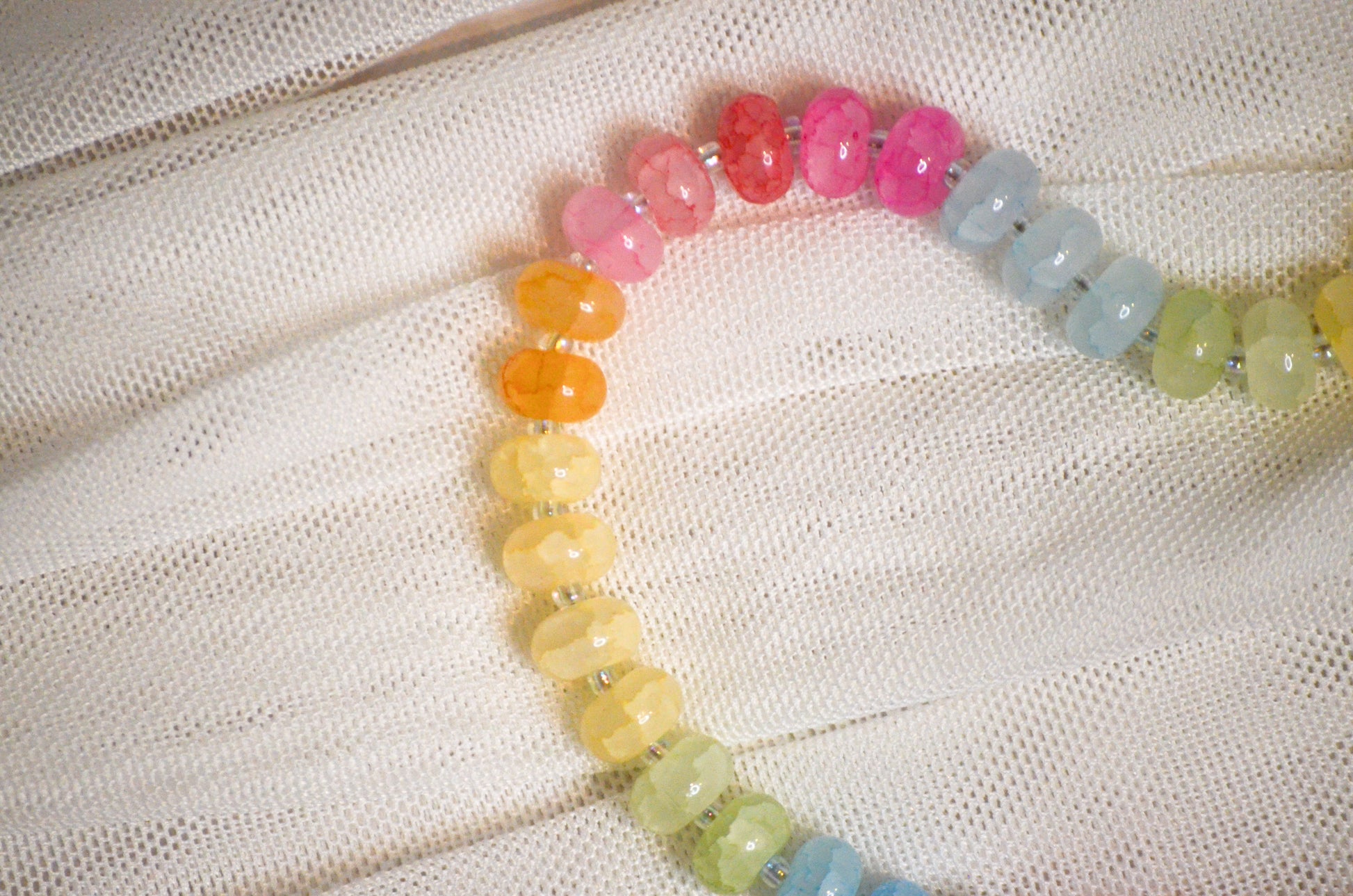 Colorful beaded necklace on a textured white fabric background