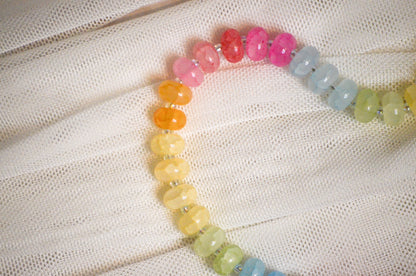 Colorful beaded necklace on a textured white fabric background