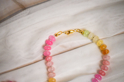Colorful beaded bracelet with a gold clasp on a white fabric background