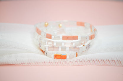 Stack of woven bracelets with pink and white pattern on a light pink background