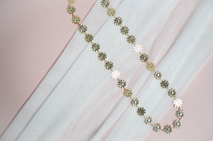 Gold necklace with floral designs on a fabric background