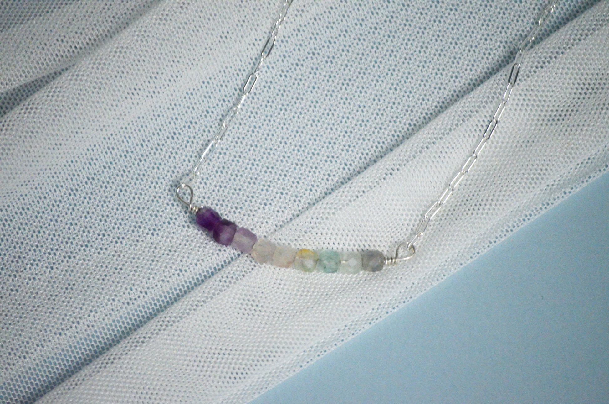 Close up image of necklace with multicolored beads on a light fabric background