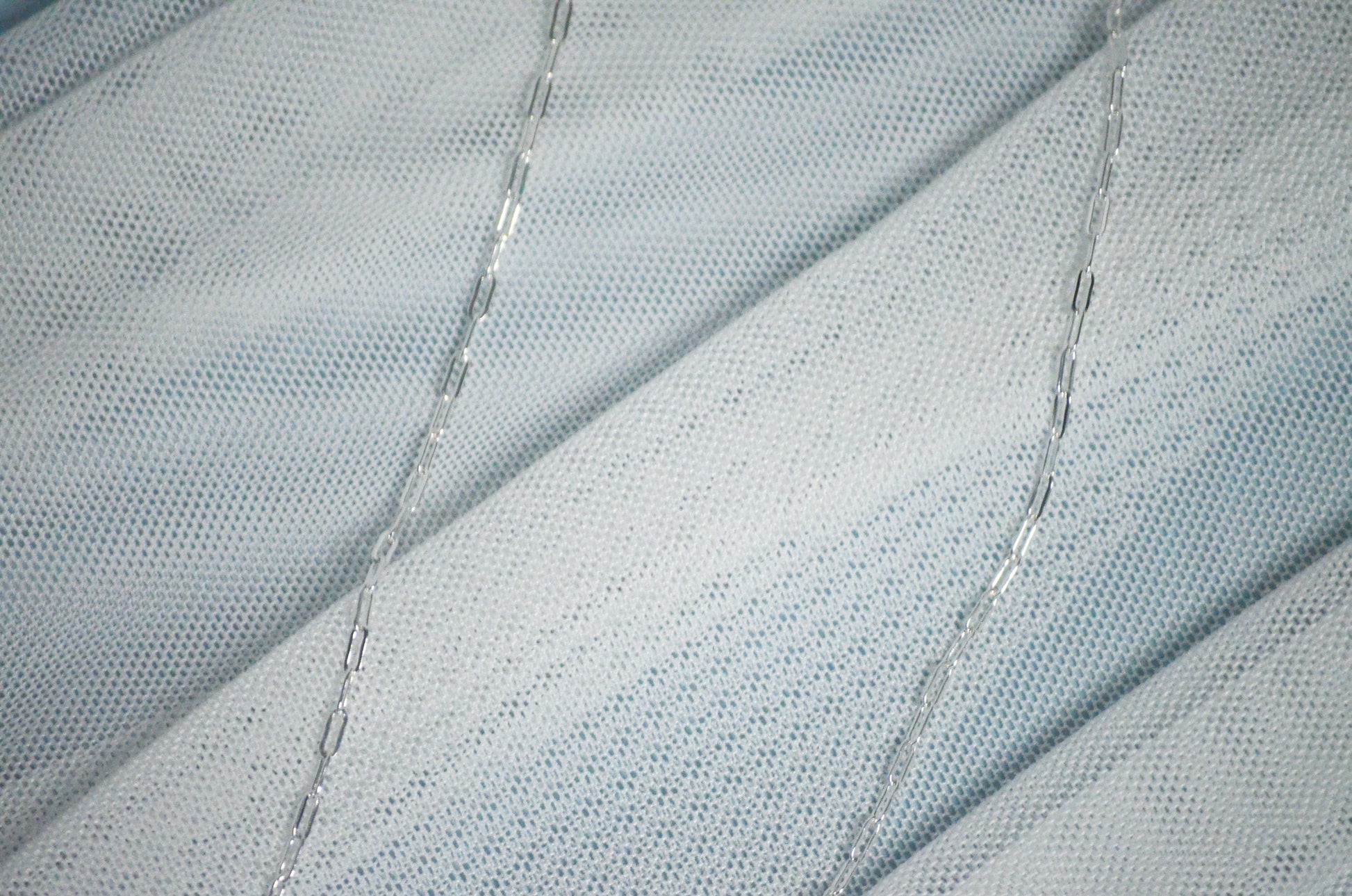 Close-up of textured fabric with a silver chain link necklace.