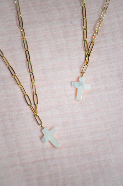 Two necklaces with cross pendants on a light pink background