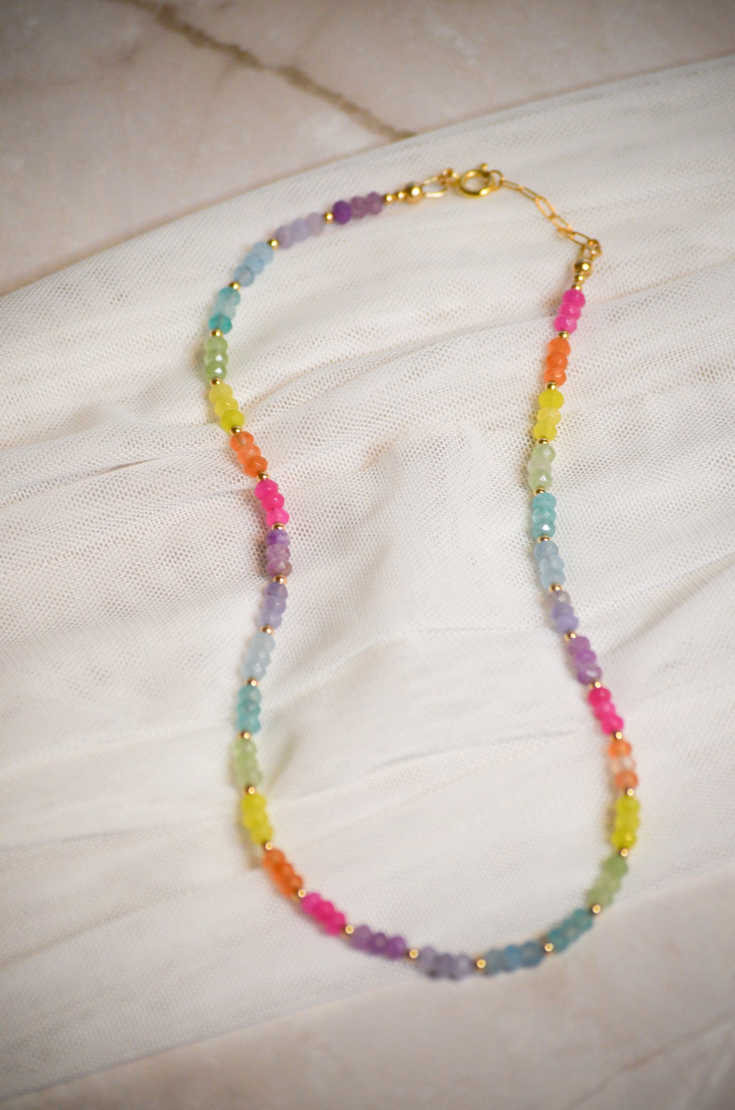 Colorful beaded necklace on a light fabric background