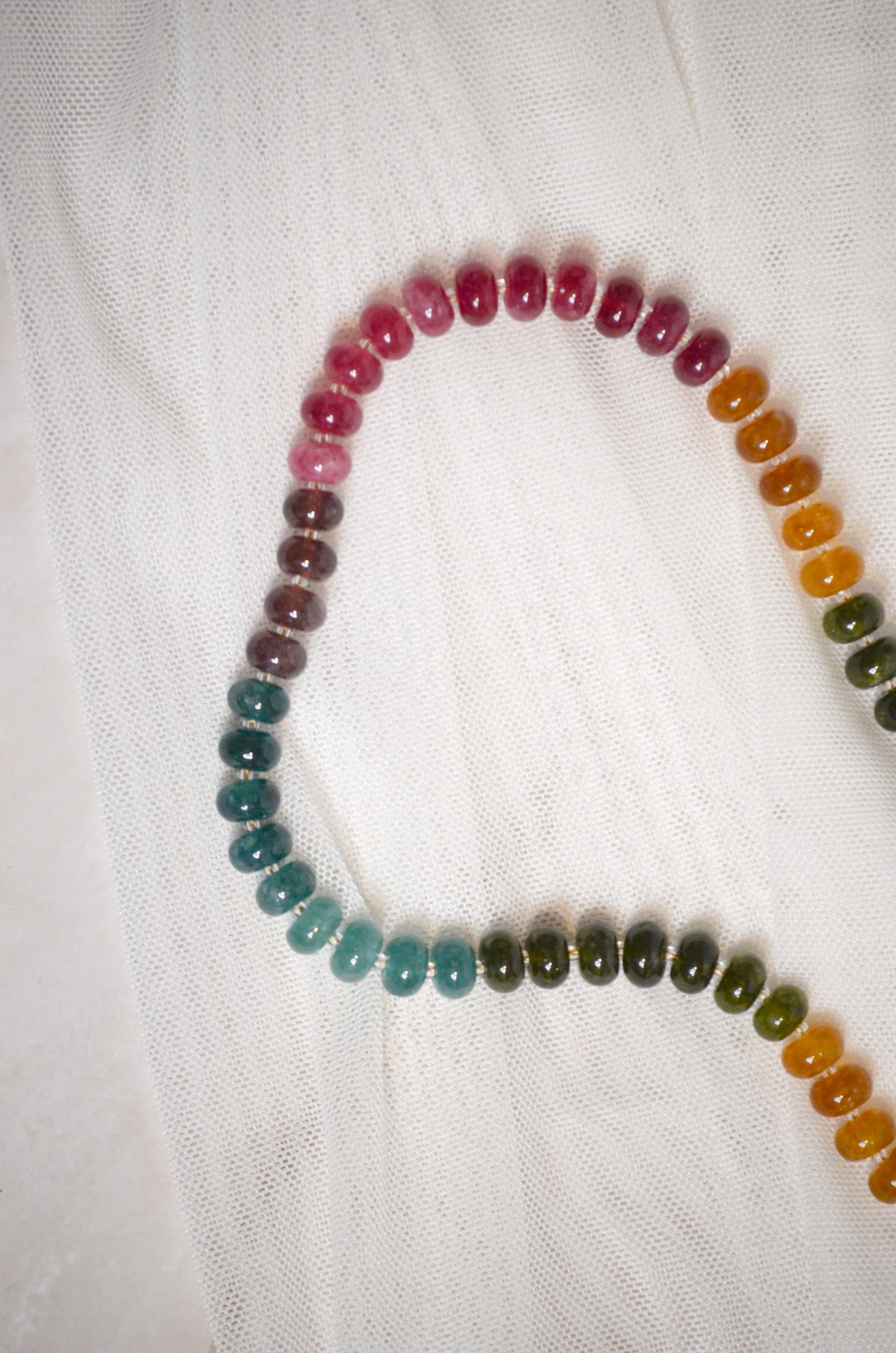 Multicolored beaded necklace on a white fabric background