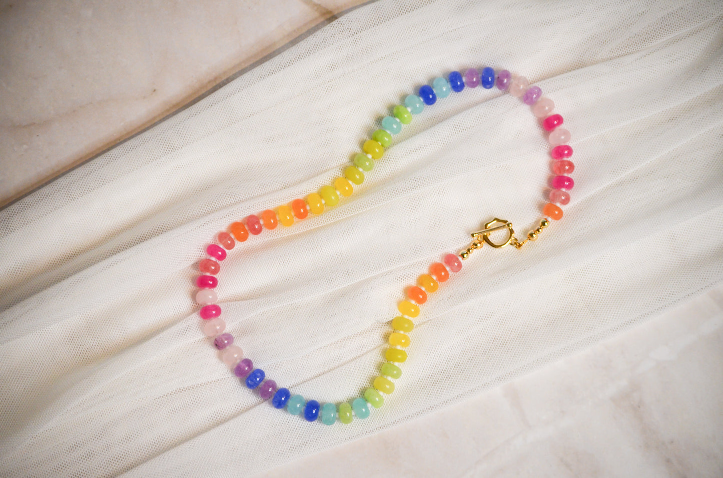Colorful beaded necklace on a light fabric background