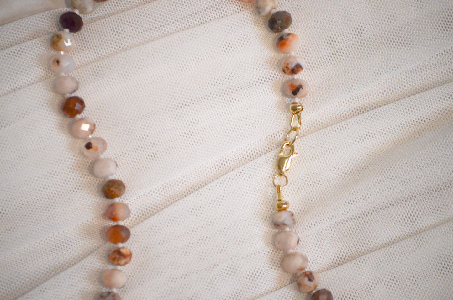 Necklace with beaded chain on a textured white surface