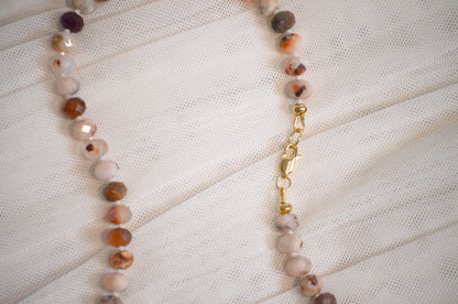 Necklace with beaded chain on a textured white surface