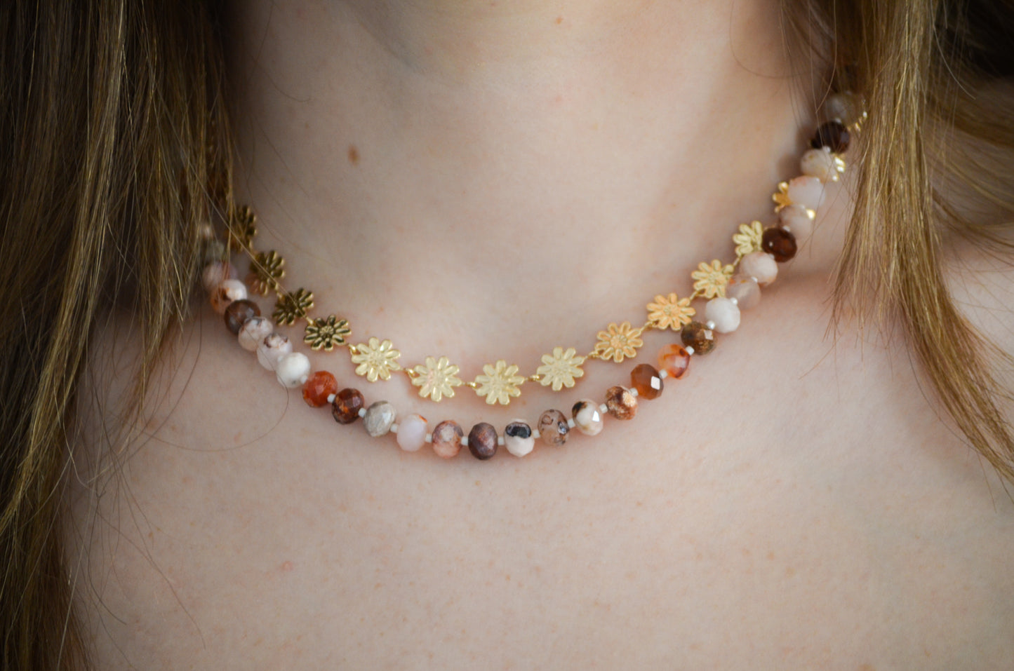 Necklace with floral chain and sakura beads worn by a woman