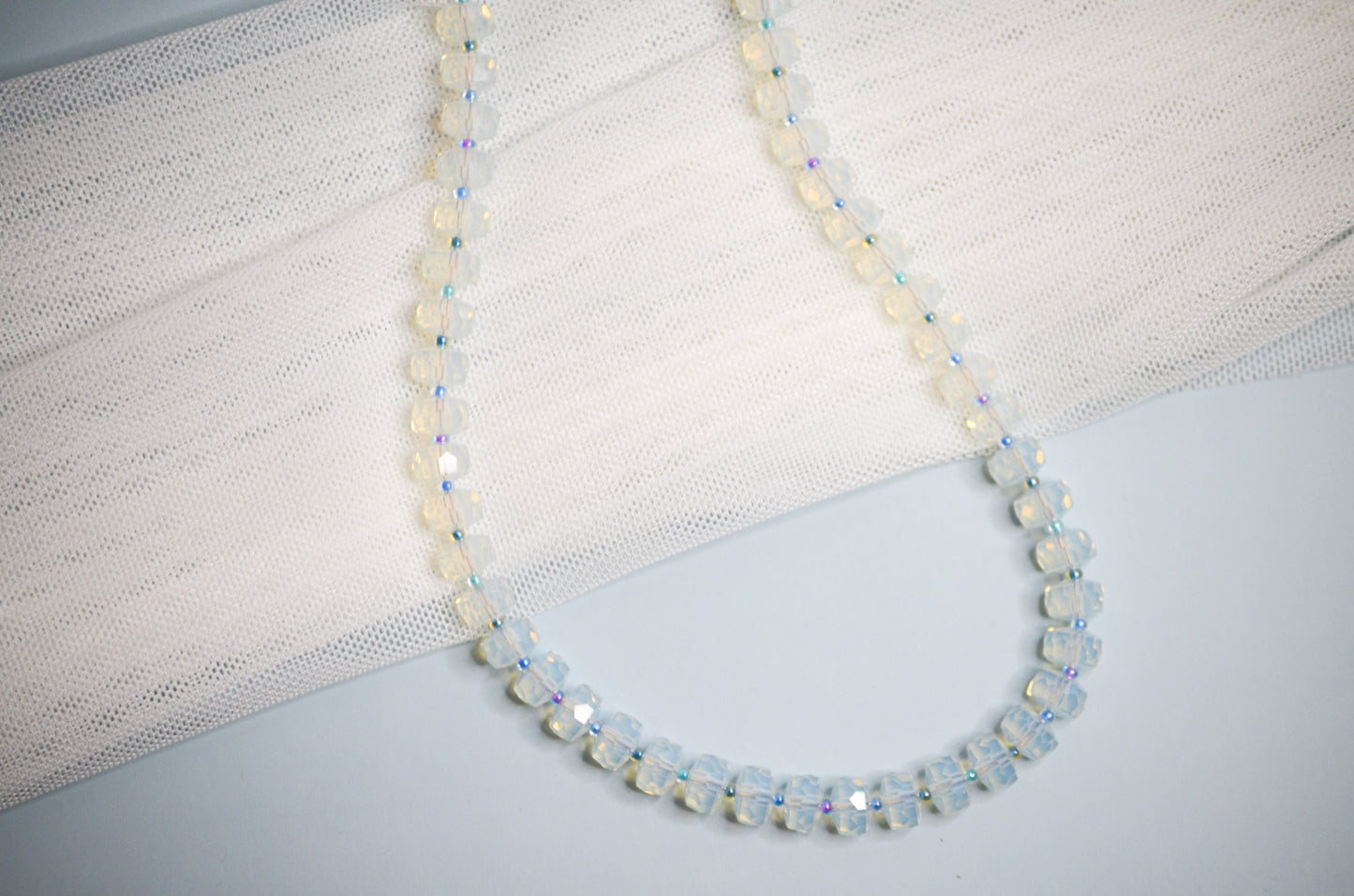 Necklace with medium sized polite beads and small cool toned beads in between on a light background