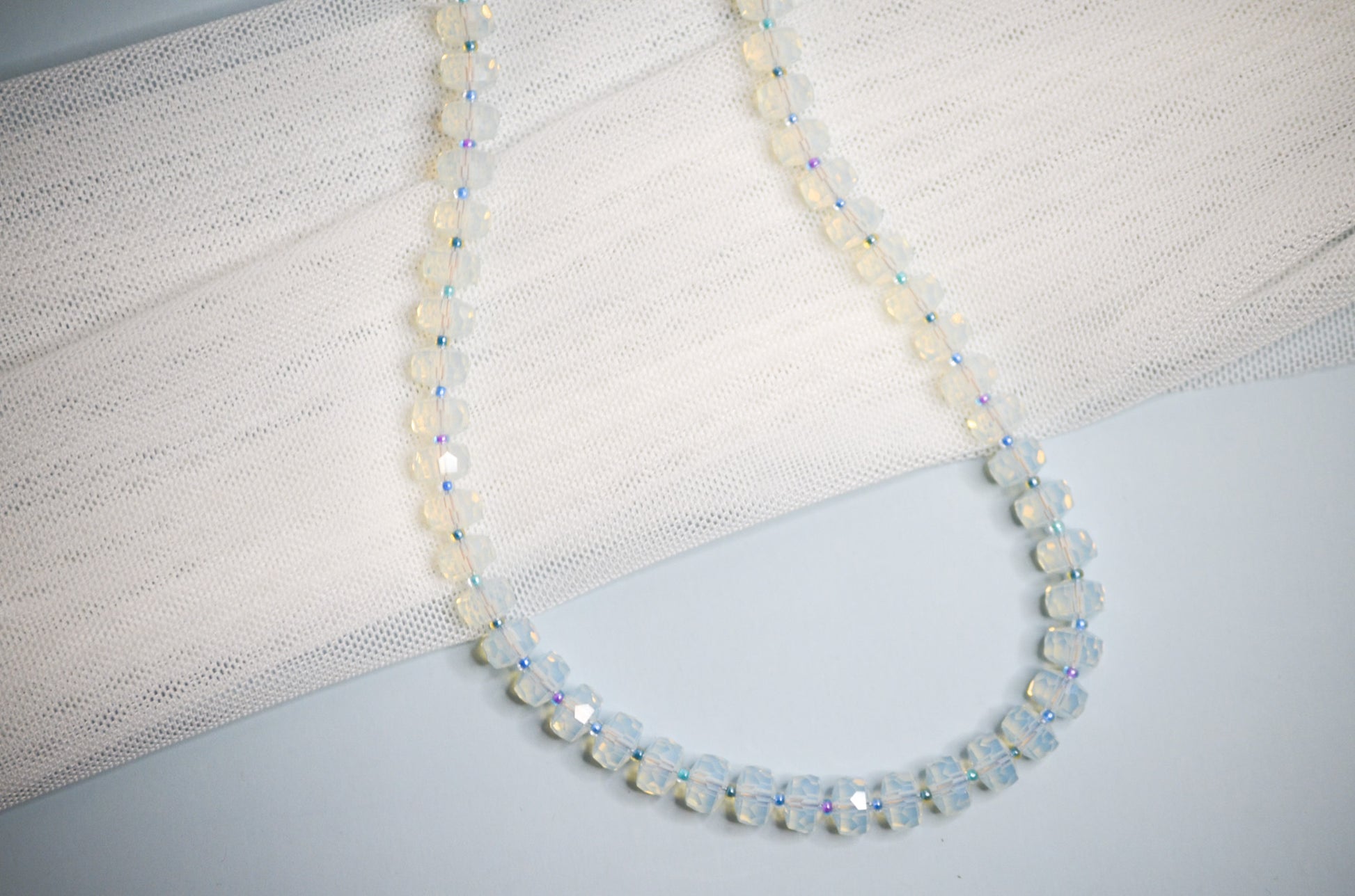 Necklace with medium sized polite beads and small cool toned beads in between on a light background