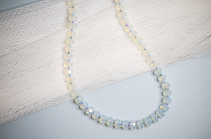 Necklace with medium sized polite beads and small cool toned beads in between on a light background