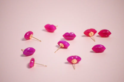 Pink lip-shaped with gold post earrings on a pink background