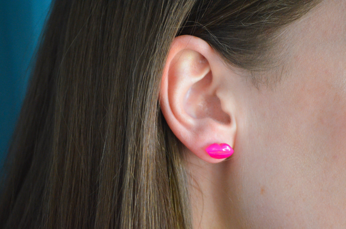 Close-up of an ear wearing a pink earring with blurred background