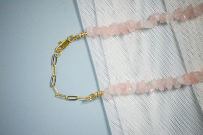 Necklace with pink gemstones and gold chain and clasp on a textured white surface