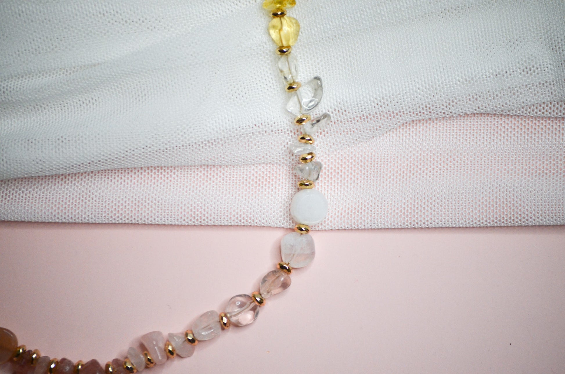 Necklace with warm toned and gold beads on a light fabric background