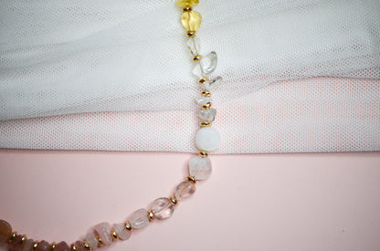 Necklace with warm toned and gold beads on a light fabric background