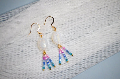 Iridescent earrings with colorful pink and blue accents on a textured white surface