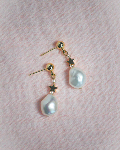 Pearl earrings with gold accents on a pink background